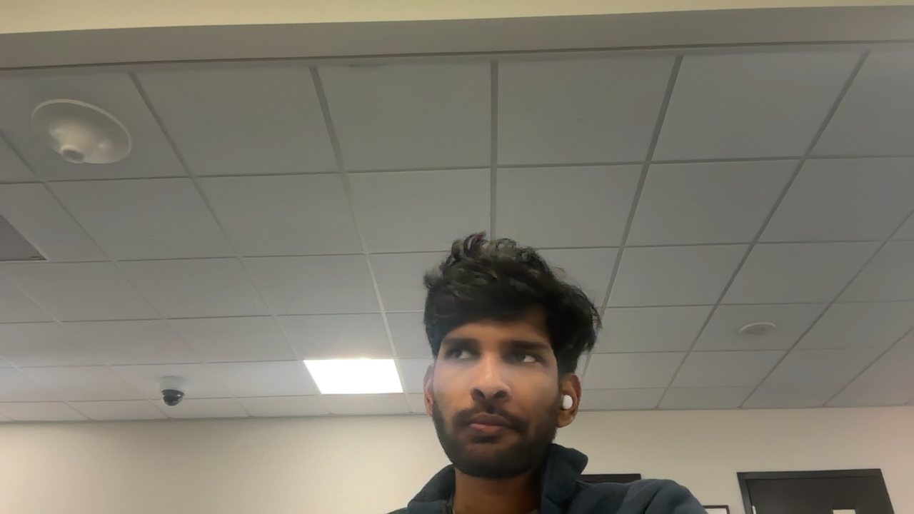 Webcam photo of Akshay at an office desk, looking at the screen